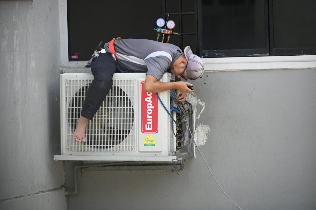 Man in Gray T-shirt Fixing the Aircon